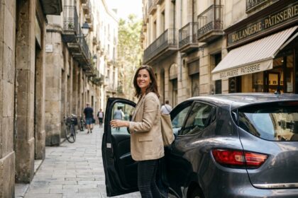 Femme sortant d'une petite citadine garée dans une rue pavée d'un centre-ville européen, sac en toile à la main, ambiance urbaine authentique